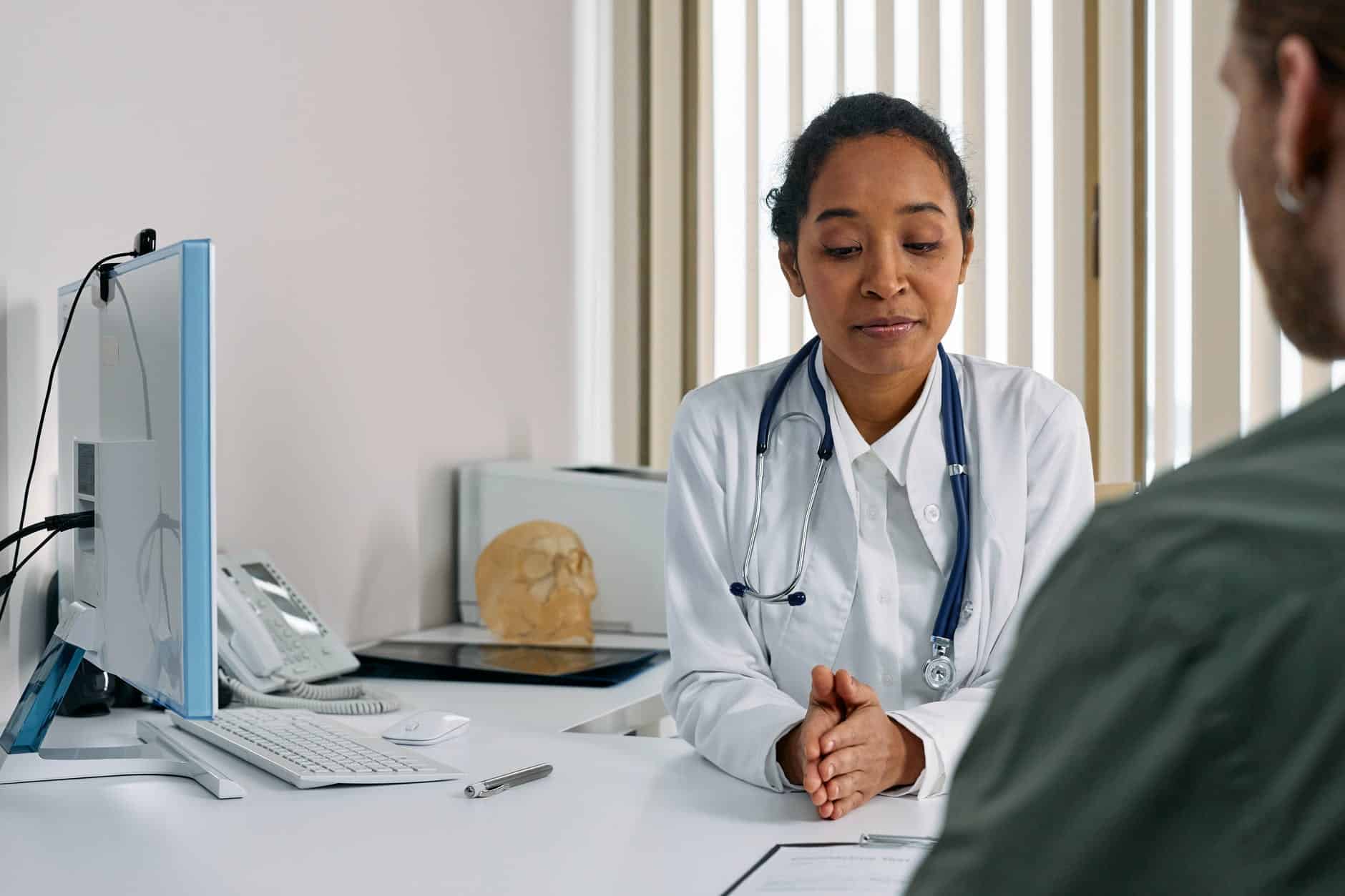 woman in white suit with stethoscope talking to a person